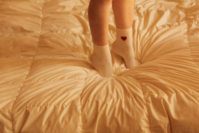 Low section of woman relaxing on bed