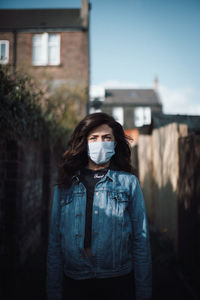 Portrait of young woman standing against built structure