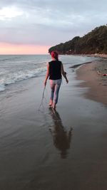 Rear view of woman walking at beach