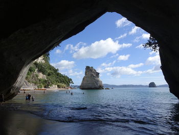 People enjoying at beach seen through cave