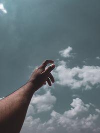 Low angle view of man hand against sky