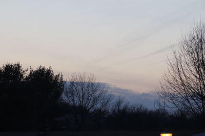 Silhouette of bare trees against sky at sunset