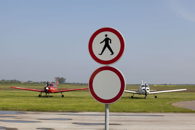 Road sign at airport runway against clear sky