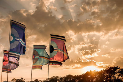Low angle view of flags against cloudy sky during sunset