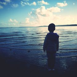 Rear view of man looking at sea against sky