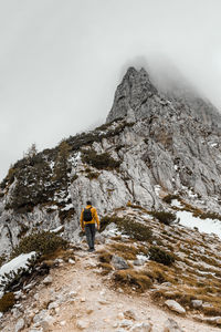 Rear view of man walking on mountain against sky