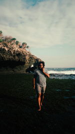 Full length of woman standing on beach against sky during sunset