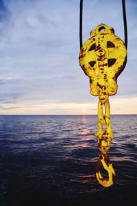 Close-up of yellow hanging by sea against sky