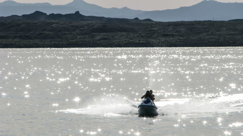 Man with woman riding jet boat on lake