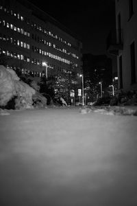 Illuminated road by buildings in city at night