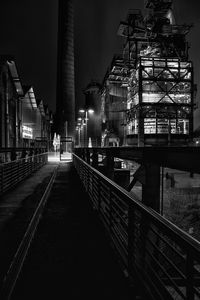 Illuminated railroad tracks amidst buildings in city at night