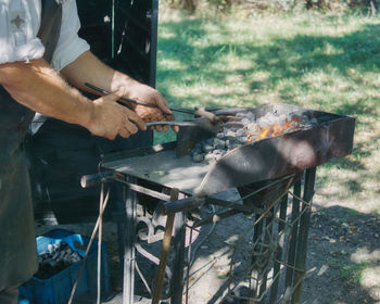 Midsection of man preparing food on barbecue