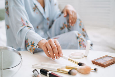 Close up photo of women's hand with makeup brushes at home, selective focus