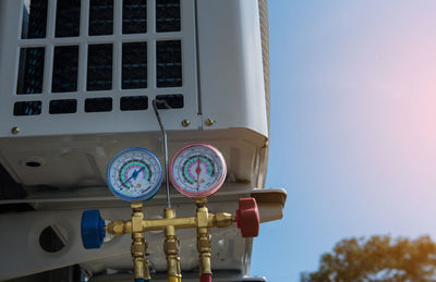 Low angle view of gauges on air conditioner against blue sky