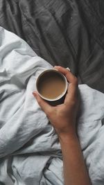 Midsection of woman holding coffee cup on bed