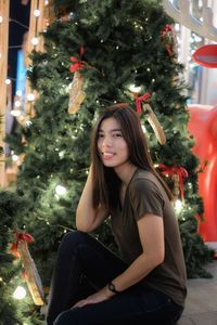 Young woman in illuminated christmas tree