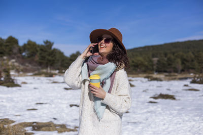 Young woman wearing sunglasses standing on snow