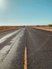 Road amidst field against clear sky