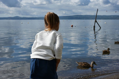 Rear view of girl standing at lakeshore