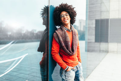 Portrait of happy young man leaning on modern building