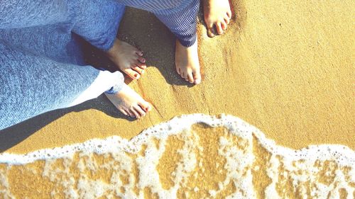 Low section of people standing on sand at beach