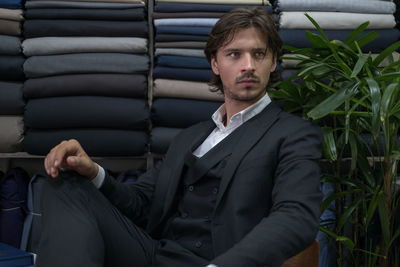 Young businessman looking away while sitting at fabric shop