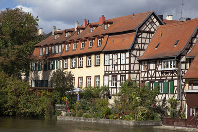 Houses by river and buildings against sky