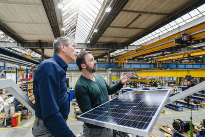 Businessmen with solar panel having discussion in factory