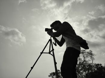 Side view of silhouette man photographing against sky
