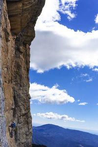 Man climbing mountain against sky