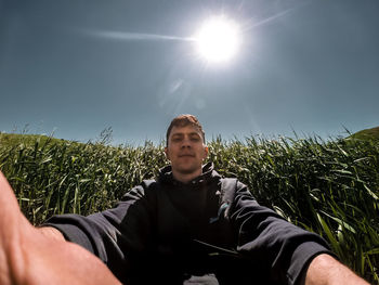 Young man standing on field against sky on sunny day