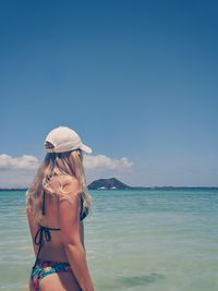 Young woman in bikini on beach against sky