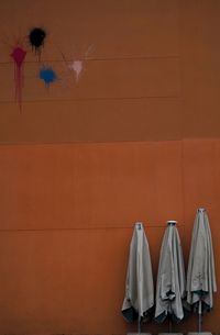 Closed umbrellas against orange wall