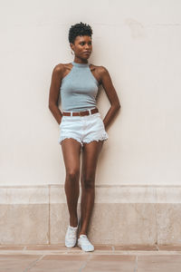 Portrait of teenage girl standing against wall