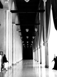 Rear view of woman walking in illuminated corridor