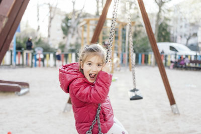 Portrait of girl on swing in playground