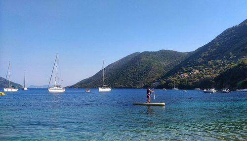 Sailboats in sea against clear blue sky
