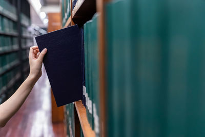 Close-up of hand removing book from shelf in library