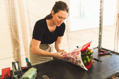 Female worker making bouquet at market stall