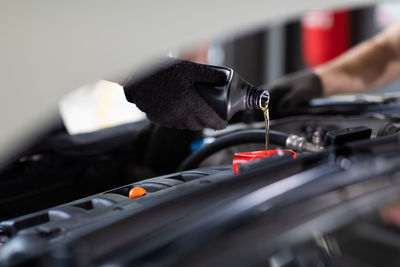 Cropped hand of mechanic pouring oil in car