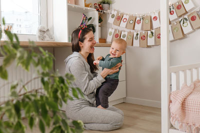 Mother with infant child having fun christmas advent calendar tasks and gifts. baby boy excited