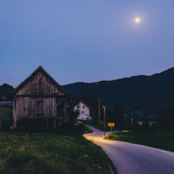 Houses and road against clear blue sky at night