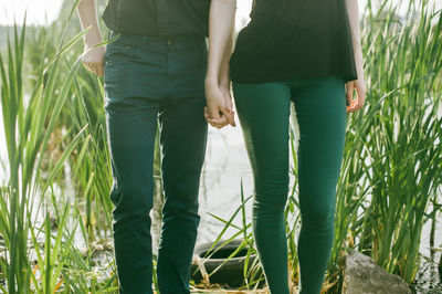 Midsection of couple standing at lakeshore