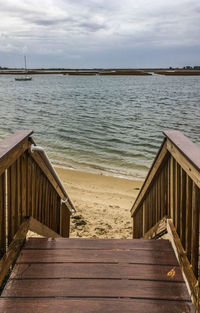 Staircase leading towards sea against sky