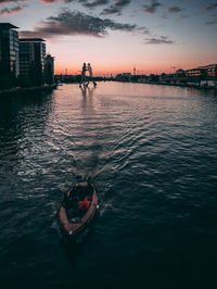 High angle view of boat on river in city during sunset