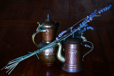 Small pewter jugs with a sprig of lavender placed on a wooden table