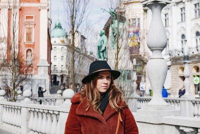 Woman looking away standing by railing in city during winter