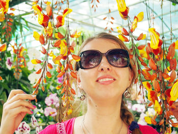 Young woman wearing sunglasses amidst orchids in greenhouse