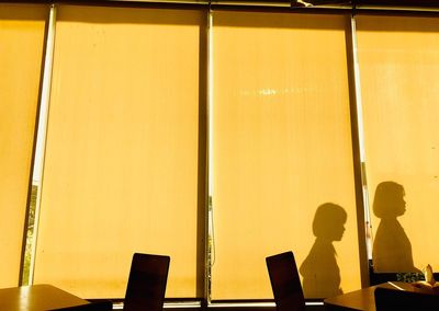 Shadow of man on table against orange wall