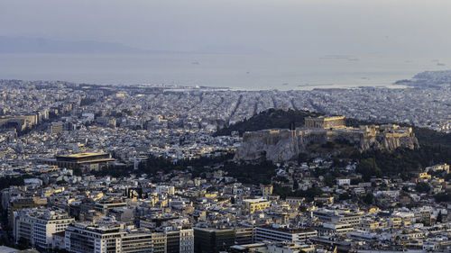 High angle view of city of athens with prominently placed acropolis against sky